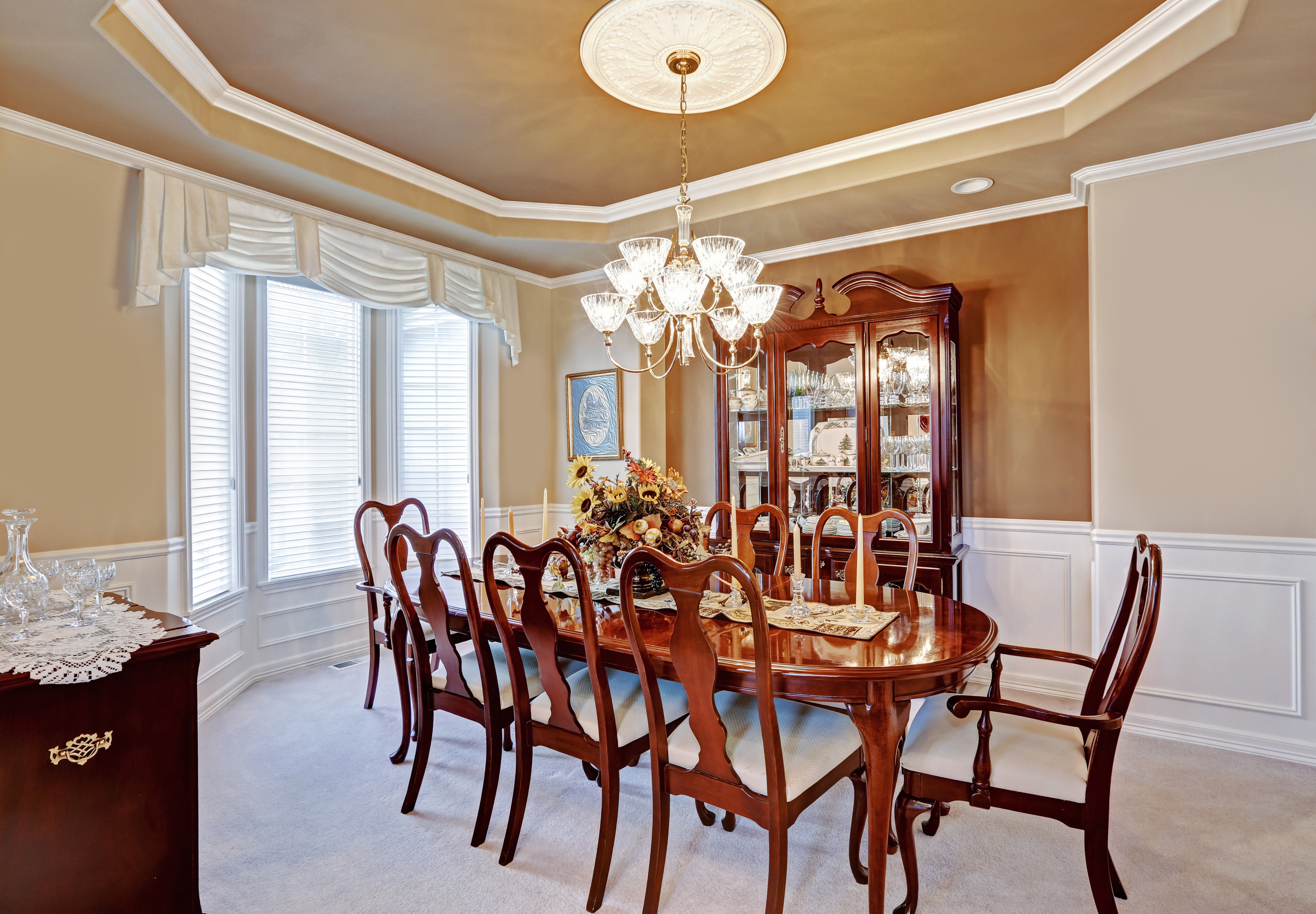 Beautiful dining room interior in luxury house. Wooden dining table set blend perfectly with light brown walls and white trim